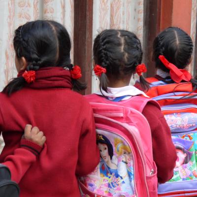 Students in Nepal wait patiently in a line for their Childcare volunteer Children line up with their backpacks outside their classroom in Nepal
